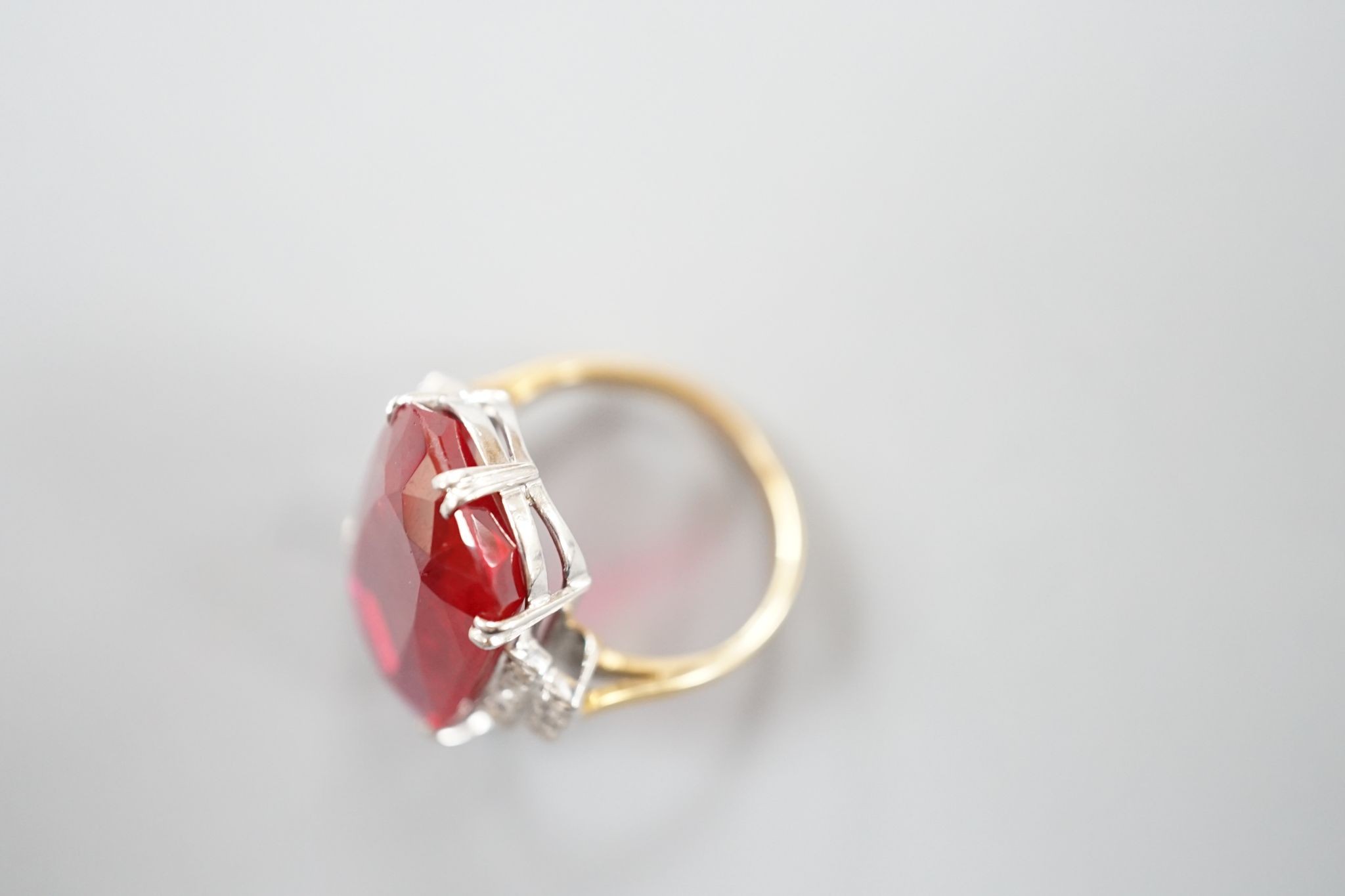 A yellow metal and large synthetic ruby set dress ring, with rose cut diamond set stepped shoulders, size L/M, gross weight 8 grams.